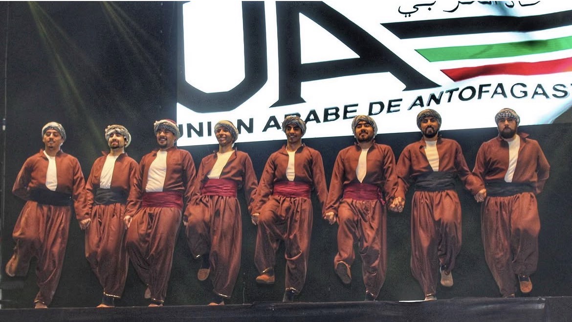 Al Ard al Baiida dancers linked together during a stage performance
